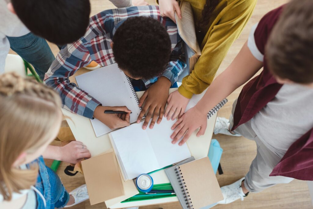 top view of high school students helping their classmate with homework